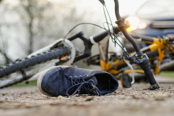 Close-up of a sneakers on the road near bicycle after car accident.
